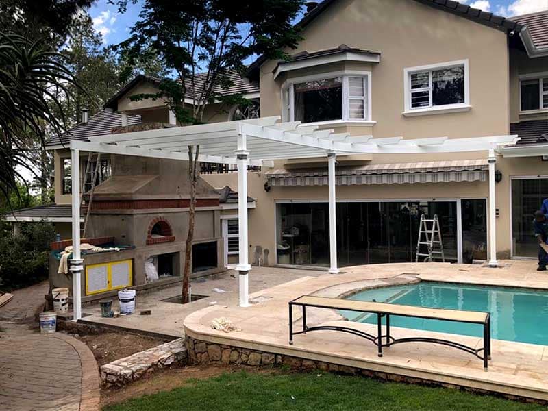 Customised steel pergola frame over a pool and pizza oven area