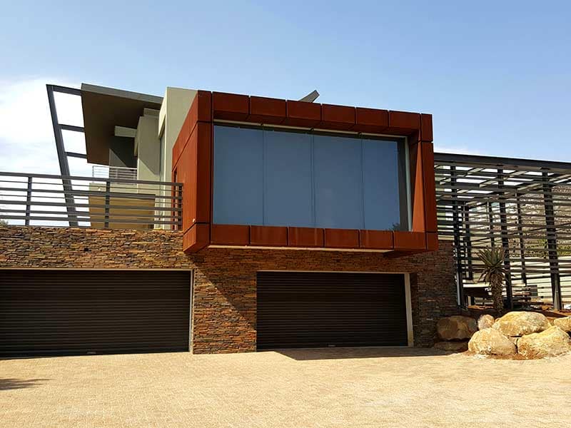 Boxed office clad in Corten steel projecting from the side of a house